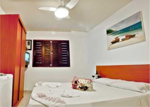 a bedroom with a large white bed with a wooden headboard at Pousada Beija Flor in Natal