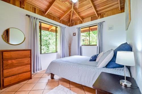 ein Schlafzimmer mit einem Bett und zwei Fenstern in der Unterkunft Bromelia House in San Gerardo