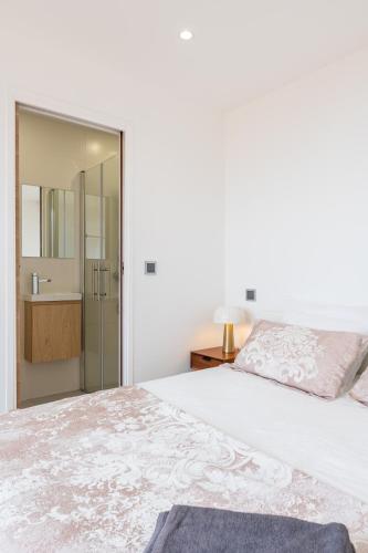 a white bedroom with a large bed and a bathroom at SUPERBE PENTHOUSE PROCHE MONACO GRANDE TERRASSE in Beausoleil