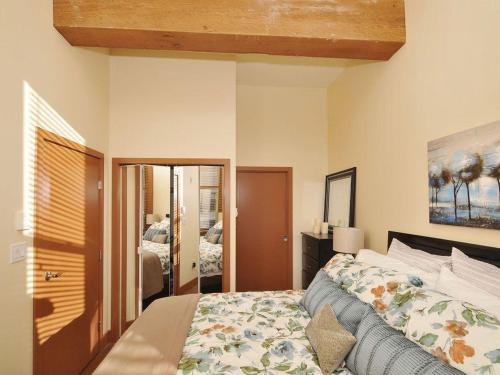 1 dormitorio con cama y espejo en Just Listed! Gorgeous Luxury 2 Bedroom, 2 Bath Condo In Old Town Victoria en Victoria