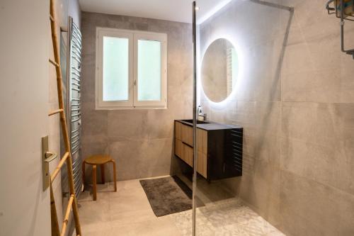 een badkamer met een glazen douche en een spiegel bij L'Alérion in Nancy