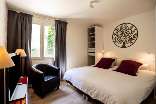 een slaapkamer met een bed, een stoel en een raam bij L'Alérion in Nancy