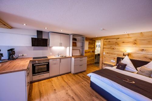 um quarto com uma cama e uma cozinha com paredes de madeira em Gästehaus Holzer Kreuz- Vergissmeinnicht em Fröhnd
