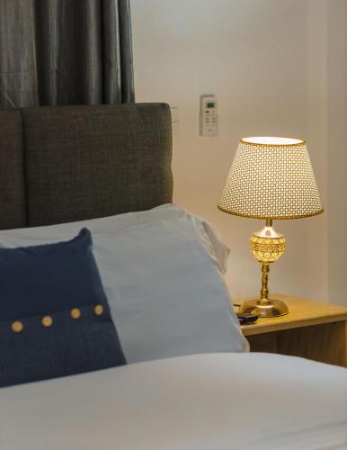 a bedroom with a bed with a lamp on a night stand at Cozy Apartments at East Airport in Burma Camp
