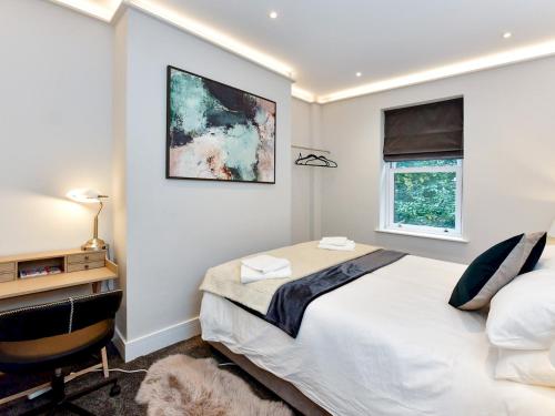 a bedroom with a bed and a desk and a window at Pass the Keys Stunning 2 Bedroom Apartment in Heart of Pontcanna in Cardiff