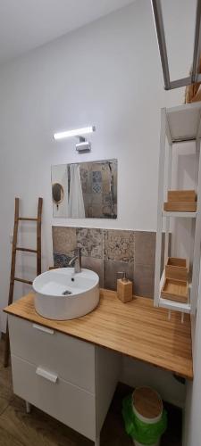 a bathroom with a white sink on a wooden counter at Appartement chaleureux en Ardèche in Châteaubourg