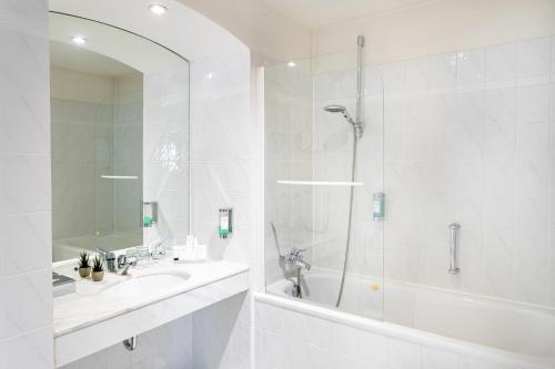 a white bathroom with a tub and a sink and a shower at Hotel Am Mühlenteich in Schwelm