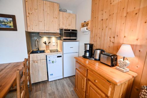 cocina con armarios de madera y nevera blanca en 24 M With Terrace Near The Center And The Slopes, en Saint-Gervais-les-Bains