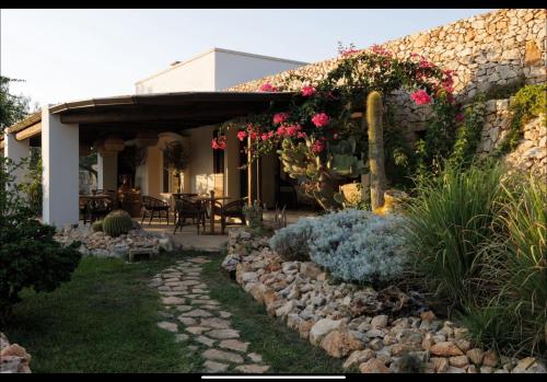 a house with a stone wall and flowers on it at Tenuta Negroamaro in Gallipoli