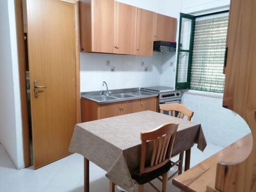 eine Küche mit einem Tisch, Stühlen und einem Waschbecken in der Unterkunft Appartamento Bent el Rhia in Pantelleria