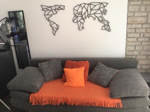 a gray couch with an orange blanket and some pillows at Sunset Villa in Siófok