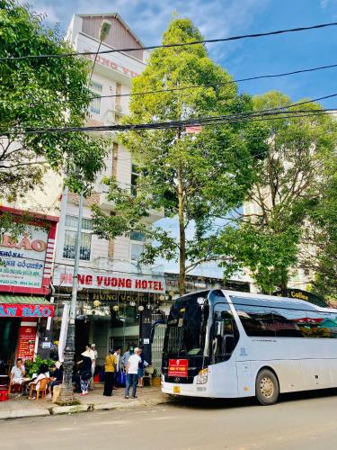 a white bus is parked in front of a store at Hung Vuong Hotel in Buon Ma Thuot