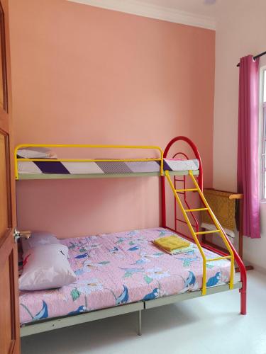 a bunk bed with a yellow frame in a room at Hana Homestay Kolam Terengganu in Marang