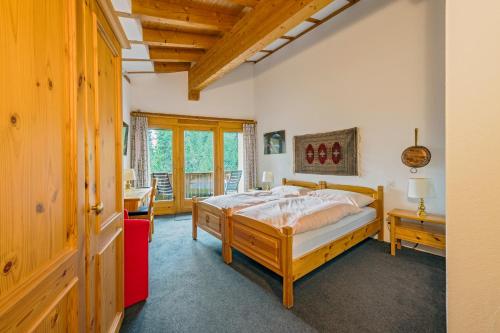 a bedroom with a bed and a desk and a window at Pra d'Sura in Maloja