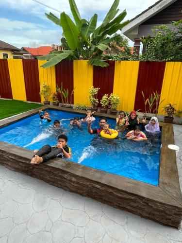un grupo de niños está en una piscina en Hana Homestay Kolam Terengganu, en Marang