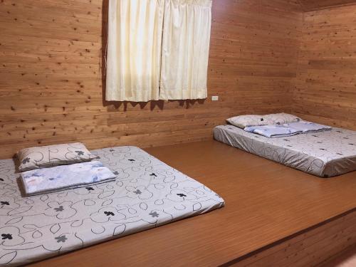 Duas camas num quarto com paredes de madeira em UT Chaung Homestay 