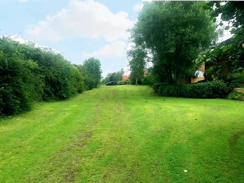 a field of green grass with a tree in the distance at Spacious 4 bed home in a quiet cul-de-sac in Coundon