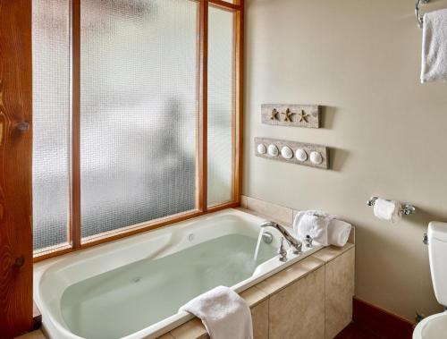 a bathroom with a tub with a window and a toilet at Beautiful Condo In A Great Location, Oceanfront Complex - Oe in Ucluelet