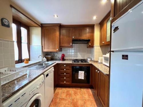 a kitchen with wooden cabinets and a white refrigerator at El Dúplex de Espot - L'Amfitriona in Espot