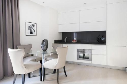 a dining room with a glass table and white chairs at Buckingham Palace Residences by Q Apartments in London