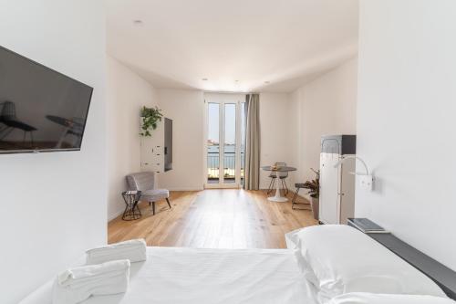 a white room with a bed and a living room at La Vacanza Ortigia in Siracusa