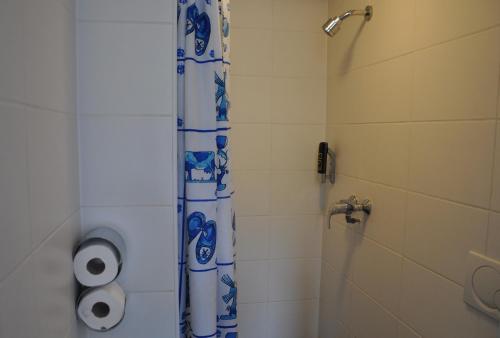 a bathroom with a shower with a blue and white shower curtain at Hotel Amsterdam Inn in Amsterdam