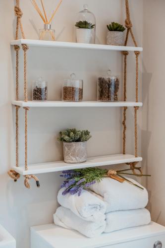 a room with white shelves with towels and plants at Lavender Lodge Bourton in Bourton on the Water