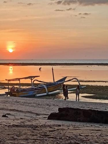 two people standing next to a boat on a beach at villa gilimakyah in Gili Air