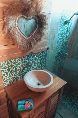 a bathroom with a sink and a heart shaped mirror at villa gilimakyah in Gili Air