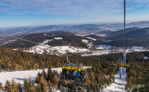 a group of people riding a ski lift in the snow at Aparthotel Apartamenty Czarna Góra 414 in Sienna