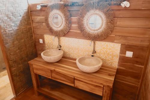 two sinks on a wooden wall with two mirrors at villa gilimakyah in Gili Air