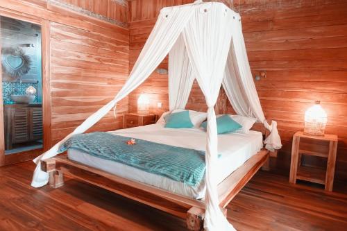 a bedroom with a bed with a mosquito net at villa gilimakyah in Gili Air