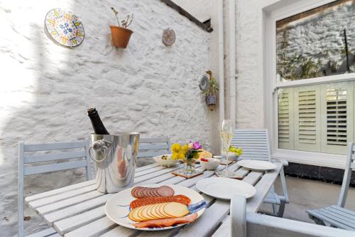 a table with a bottle of wine and a plate of food at Hope Cottage, Brixham in Brixham