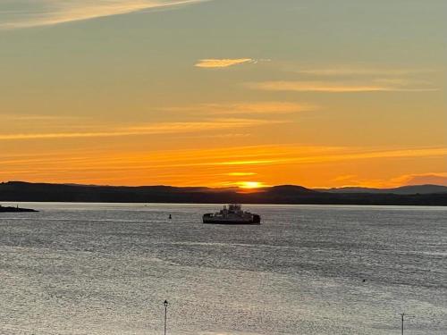 a boat in a large body of water at sunset at Penthouse Seafront Largs in Largs