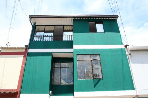 - un bâtiment vert et blanc avec deux fenêtres dans l'établissement CASA VERDE - APARAMENTOS BUCARAMANGa, à Bucaramanga