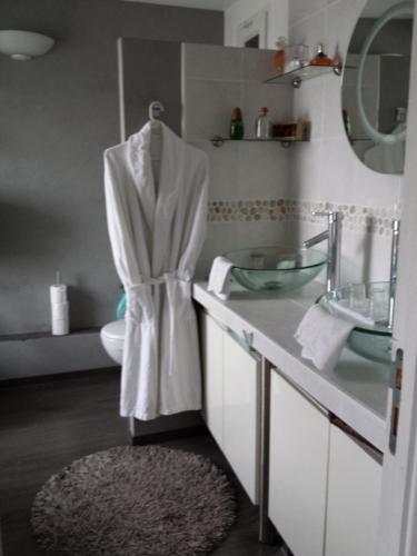 Baño con una bata blanca colgada en un espejo en Chambres d'hôtes Olry, en Nancy