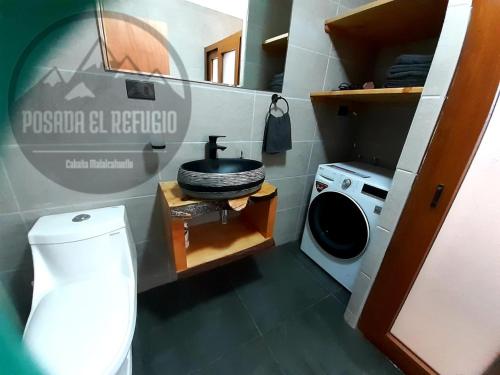 a bathroom with a toilet and a washing machine at Cabaña Posada El Refugio in Malalcahuello