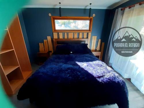 1 dormitorio con 1 cama en una habitación azul en Cabaña Posada El Refugio, en Malalcahuello
