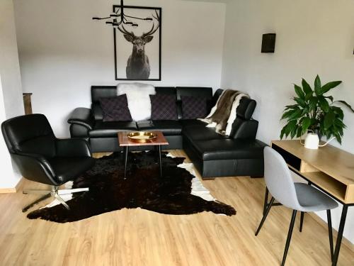 sala de estar con sofá de cuero negro y mesa en Appartement 53m2 rénové dans un chalet au coeur de Charmey avec vue sur les montagnes, en Charmey