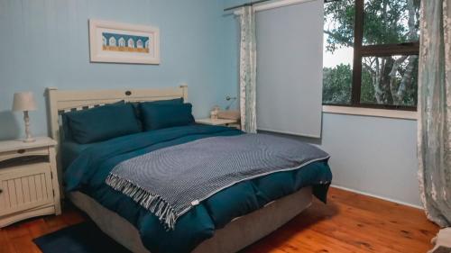 a bedroom with a bed with blue sheets and a window at Campismo Ninho Villa 26 - Ponta Malongane in Ponta Malongane