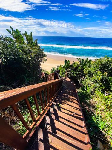 a wooden boardwalk leading to a beach with the ocean at Campismo Ninho Villa 26 - Ponta Malongane in Ponta Malongane