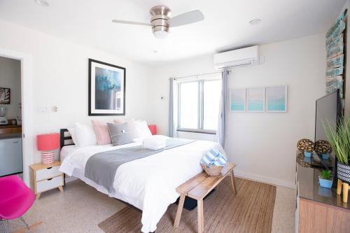 a white bedroom with a large bed and a pink chair at Casa Limonada Boutique Motel in Sarasota