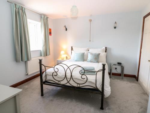 um quarto com uma cama com lençóis brancos e almofadas azuis em Oakmead em Moreton-in-Marsh