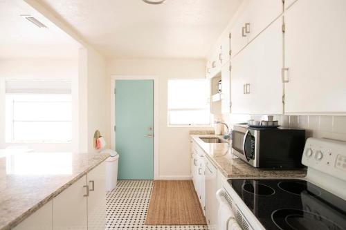 a kitchen with white cabinets and a microwave at Casa Limonada Boutique Motel in Sarasota