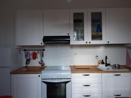 uma cozinha com armários brancos, um fogão e um lavatório em A Cento Metri dal Mare em Senigallia