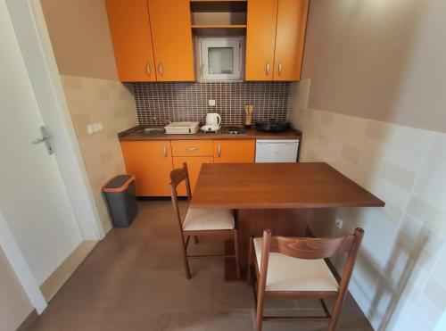 a small kitchen with a wooden table and chairs at Apartments Karla in Rogoznica