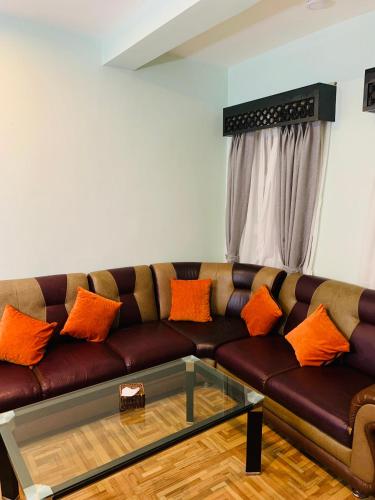 a living room with a brown couch with orange pillows at Hotel ABC, Boutique Hotel in Pokhara in Pokhara