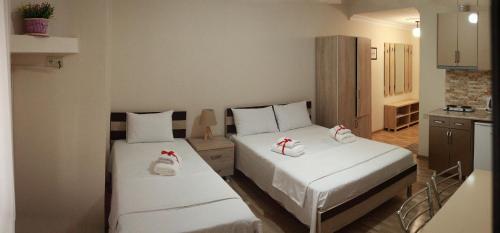 two beds in a small room with white sheets at Hotel Tao in Batumi