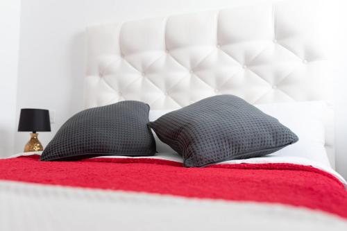 2 cuscini su un letto con coperta rossa di White House ad Arrecife