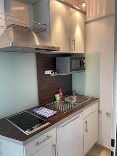 uma pequena cozinha com um lavatório e um micro-ondas em Hotelturm Apartment em Augsburg